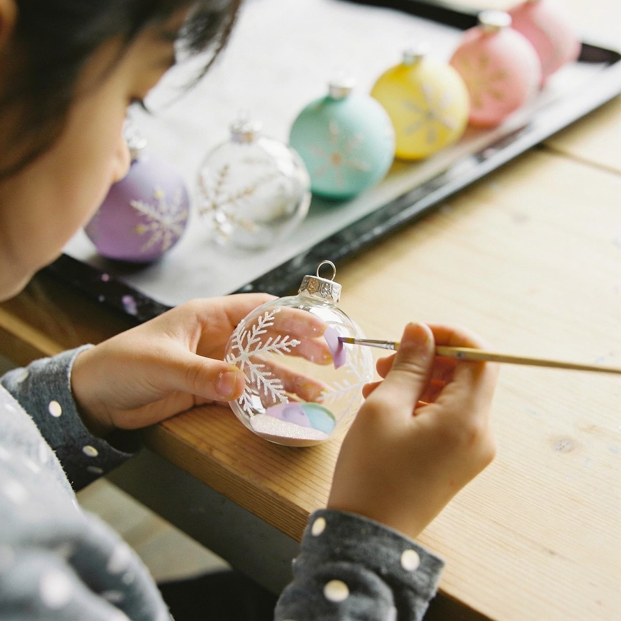 Mains d’enfant peignant une boule de Noël